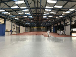 Light grey two pack epoxy floor paint top coat applied to a large factory floor on top of primer
